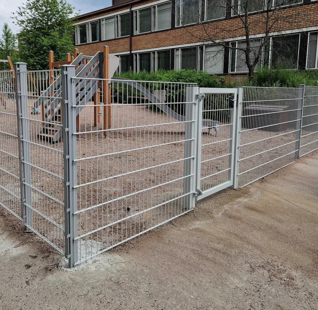 Elementtiaidassa käytetään koko pylvään pituista kiinnityslistaa ja teräskiinnikkeitä. Käyntiportissa on yhteinäinen perustusvalu